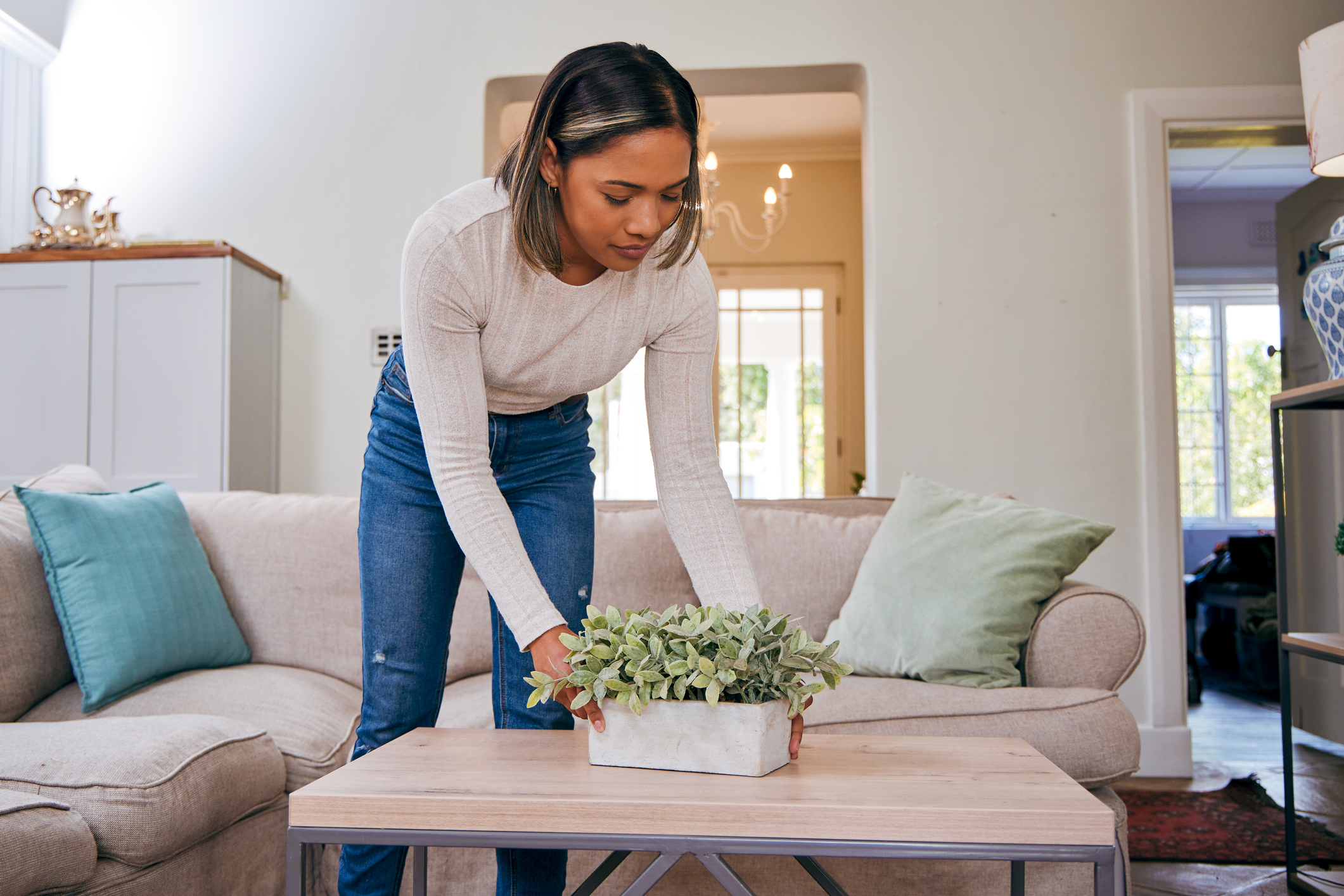 Shot of a young woman tidying her living room