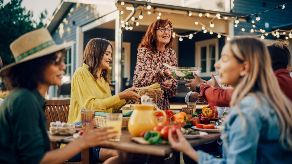 Designing a Family-Friendly Backyard. Family and Multiethnic Diverse Friends Gathering Together at a Garden Table. People Eating Grilled and Fresh Vegetables, Sharing Tasty Salads for a Big Family Celebration with Relatives.