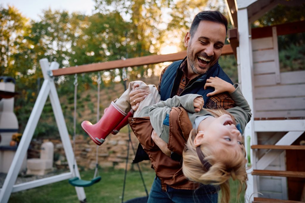 Designing a Family-Friendly Backyard. Playful father having fun with his daughter in the park in autumn.