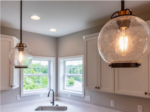 Modern kitchen interior design with round light fixtures and sink with view of outside.