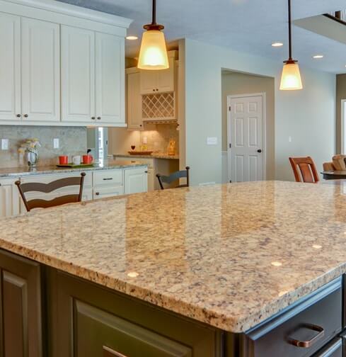Kitchen island with dark cabinetry, granite countertops, and two pendant lights above