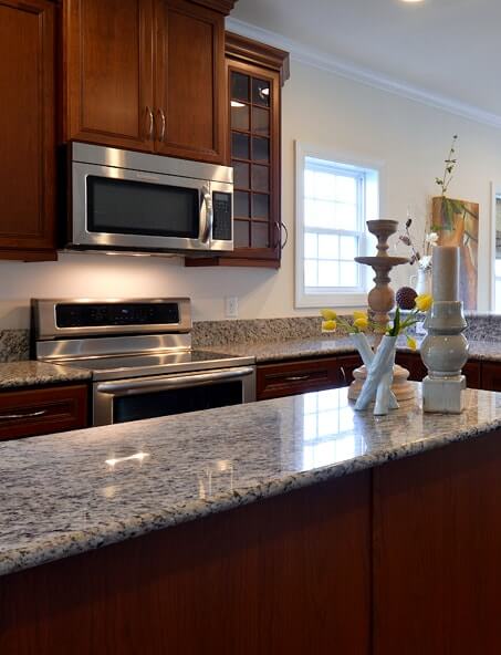 Kitchen with dark cabinetry, stainless steel appliances and center island with granite countertops