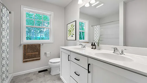 Hawthorne owner’s bathroom with dual vanity, white cabinetry, tub-shower combo, and natural light coming through window.