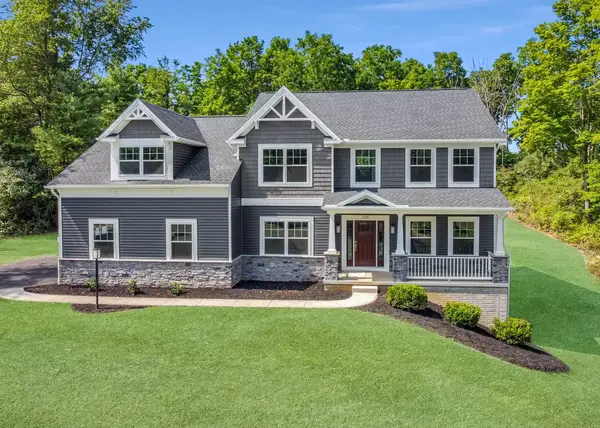 Avalon two-story home with dark siding, stone foundation, front porch, gabled rooflines, and landscaped lawn.