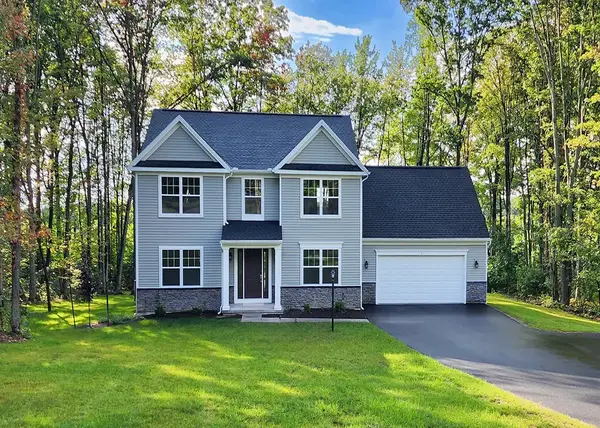 Hawthorne two-story home with light siding, stone accents, centered entry, attached garage, and wooded backdrop. 