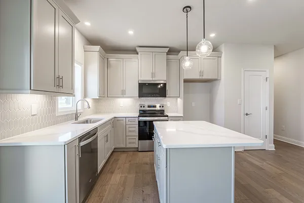 Avalon kitchen with light cabinetry, center island, stainless appliances, pendant lighting, and vinyl plank flooring.
