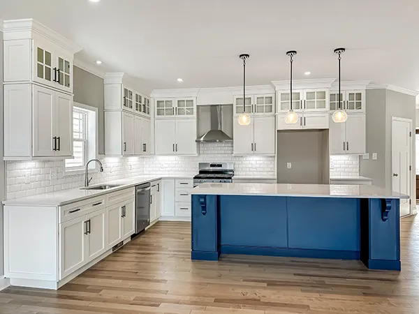 Chatham kitchen with white perimeter cabinets, blue island, quartz countertops, pendant lights, and open layout.