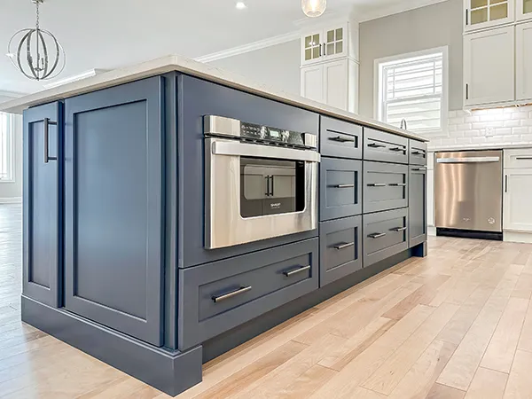 Chatham kitchen island with blue cabinetry, built-in wall oven, quartz countertop, and vinyl plank flooring.