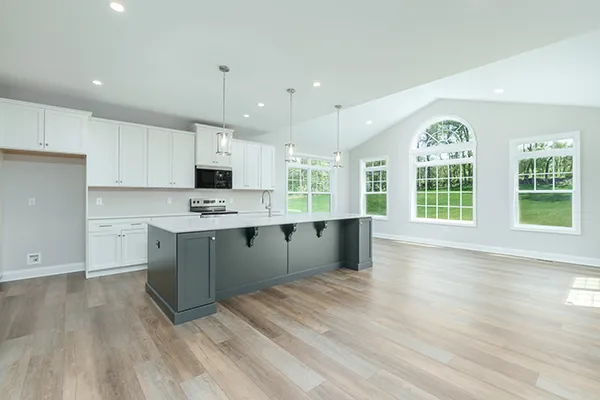 Newport kitchen with large island, white cabinetry, pendant lighting, morning room windows, and vinyl plank flooring.