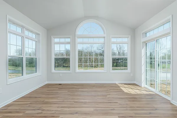 Aspen morning room with vaulted ceiling, windows on 3 sides with arched window above rear windows, with vinyl plank flooring. 
