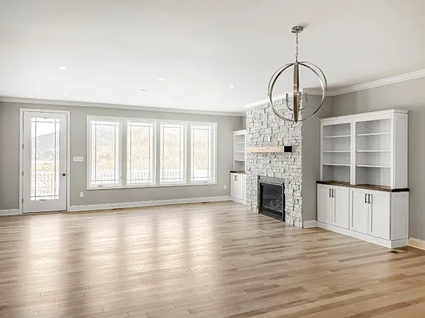 Chatham family room with custom stone fireplace, built-in cabinetry, wall of windows, vinyl plank flooring, and an unfurnished layout.